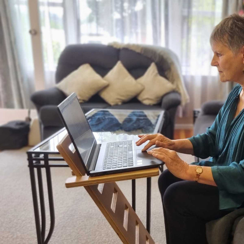 Jill is using a laptop on The Desk Stars Laptop Stand, sitting on the couch